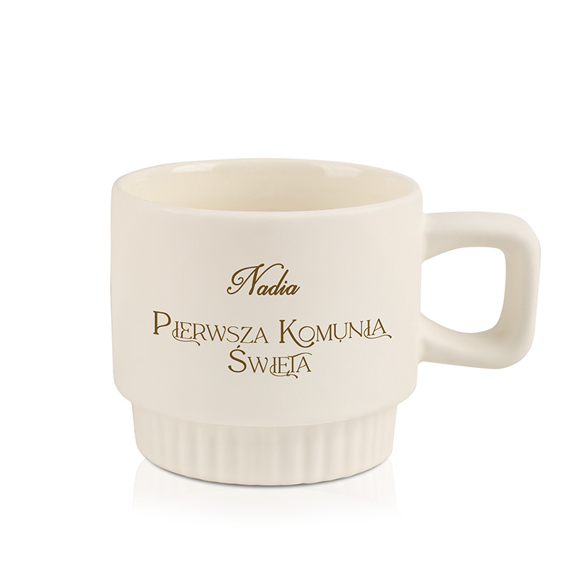 Biała filiżanka ozdobiona złotym napisem "Nadia Pierwsza Komunia Święta".