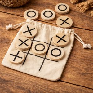 Zestaw do gry w kółko-krzyżyk na drewnianym stole, z drewnianymi żetonami w kształcie kółek i krzyżyków oraz woreczkiem.