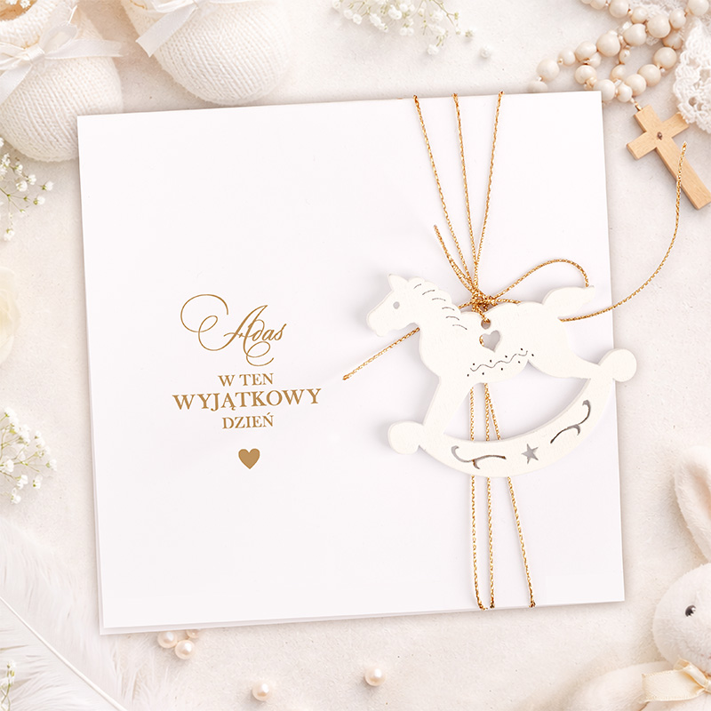 Biała kartka z napisem "w ten wyjatkowy dzień" i ozdobą w kształcie drewnianego konika na biegunach.