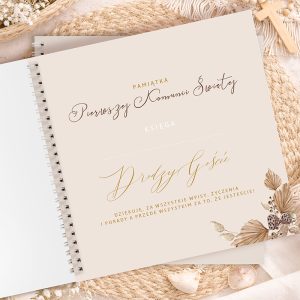 Księga pamiątkowa z napisem "Pamiątka Pierwszej Komunii Świętej" ozdobiona liśćmi i muskusem, na tle jasnym.