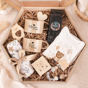 Zestaw upominkowy w kształcie heksagonu z dwoma kubkami, kawą, body dla niemowląt i dekoracyjnymi akcesoriami.