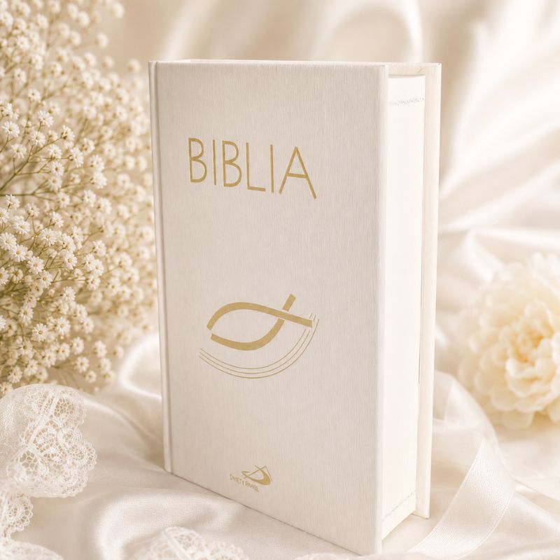 Biała Biblia z złotym napisem "BIBLIA" na okładce, jasnym tle z delikatnymi dodatkami kwiatowymi.