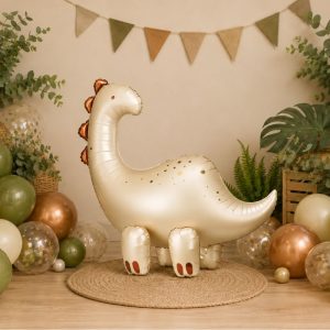 Złoty balon w kształcie dinozaura na tle dekoracji w odcieniach zieleni i brązu w przytulnym pomieszczeniu.
