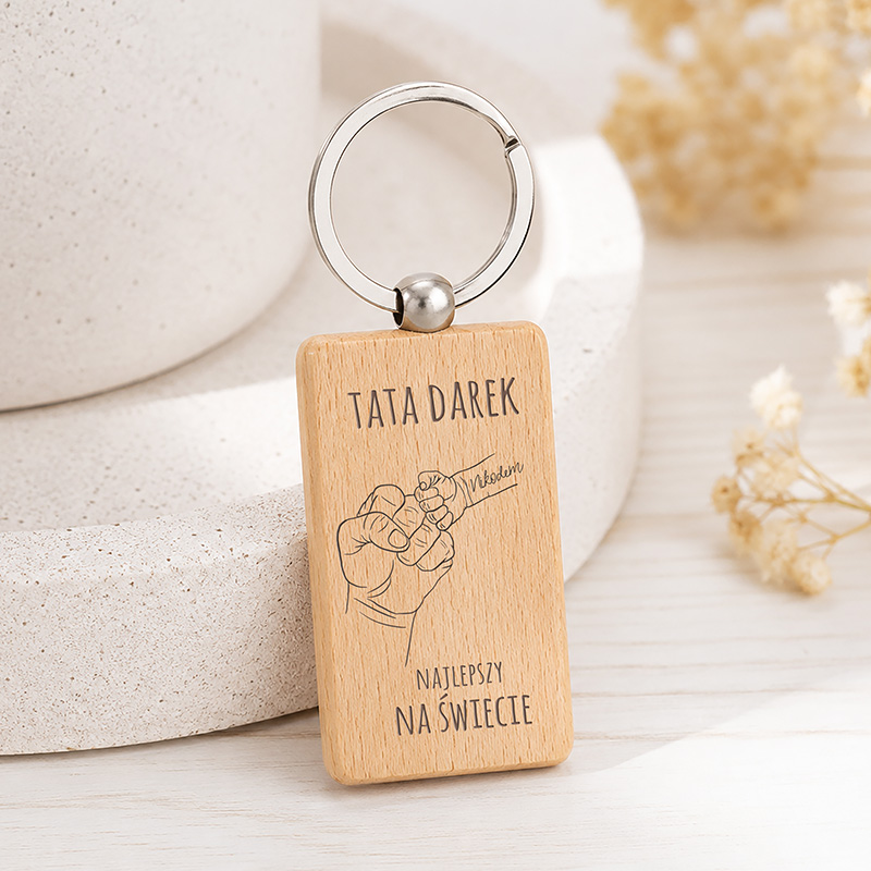 Breloczek z drewna z napisem "TATA DAREK" i rysunkiem pięści, podkreślający, że jest "NAJLEPSZY NA ŚWIECIE".