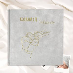 Szara okładka albumu z napisem "KOCHAM CIĘ Tatusiu" oraz rysunkiem dłoni dorosłego i dłoń dziecka.