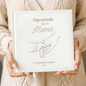 ksiazka-do-uzupelnienia-dla-mamy-z-ilustracja-dloni-na-okladce.jpg Osoba trzyma białą książkę z napisem "Opowiedz mi Mamo" oraz ilustracją dłoni dziecka trzymającej dorosłą.