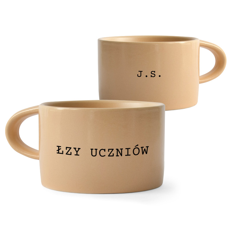 Kubek w kolorze jasnobeżowym z napisem "J.S." z jednej strony i "ŁZY UCZNIOW" z drugiej.