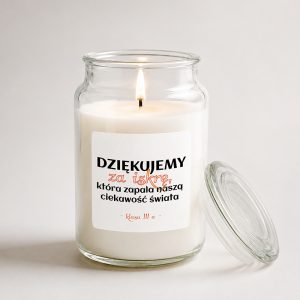 Świeca w szklanym słoiku z napisem "Dziękujemy za iskry, która zapala naszą ciekawość świata", płonąca wewnątrz.