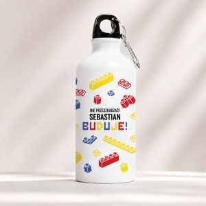 Biały bidon z imieniem, kolorowymi klockami Lego i karabińczykiem.