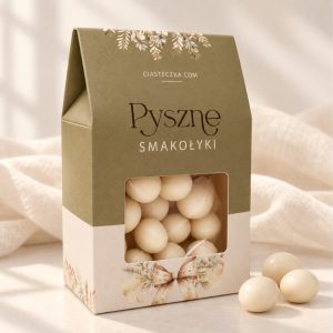 Draże w ozdobnym oliwkowo-kremowym pudełeczku z przezroczystym okienkiem, roślinną dekoracją i napisem „Pyszne Smakołyki” jako słodkie podziękowanie dla gości.