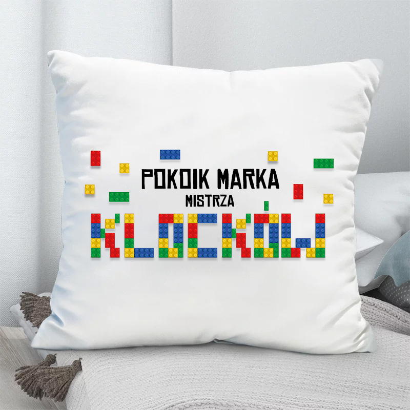 Biała poduszka z imieniem i kolorowym motywem klocków.